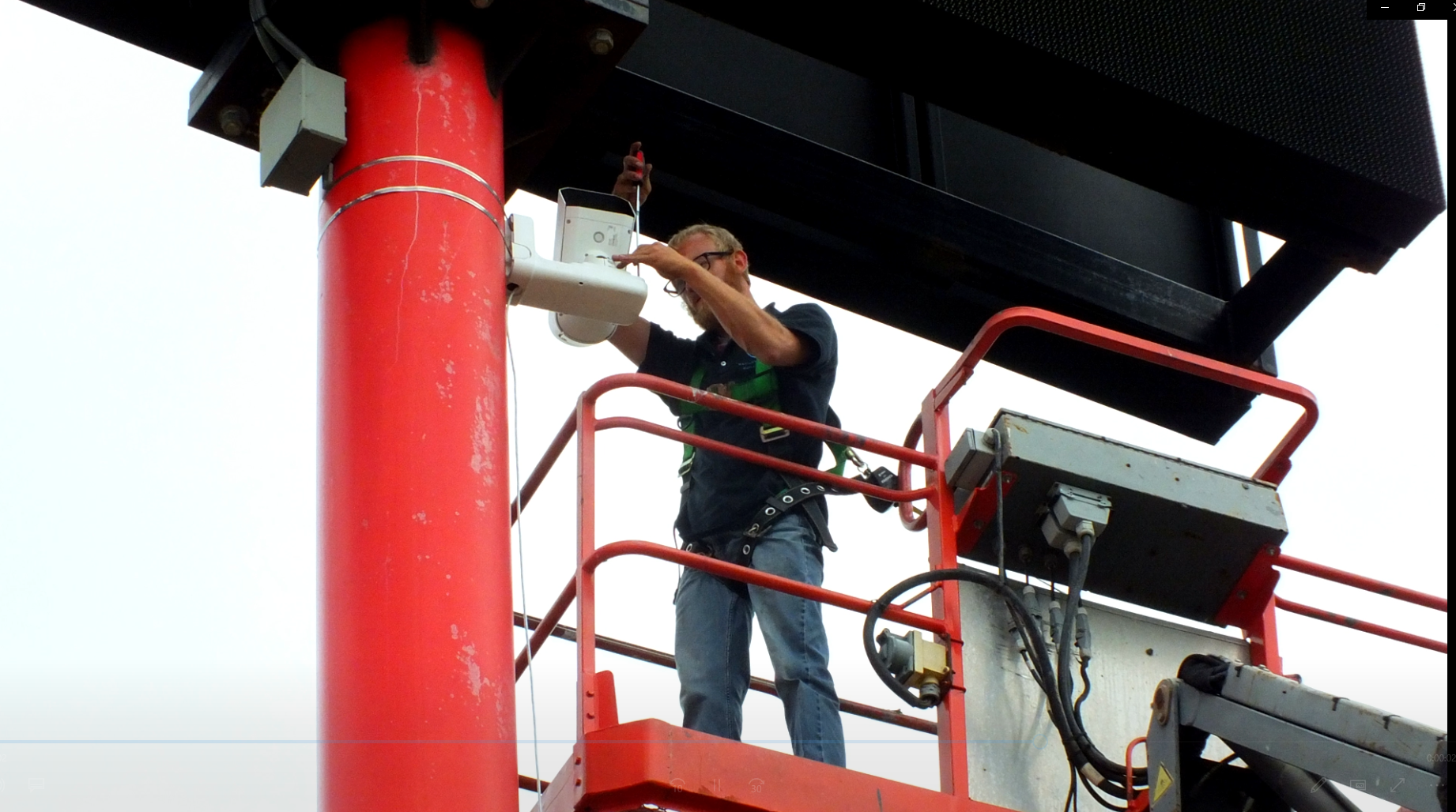 Field technician servicing exterior equipment from a lift